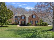 Charming two-story brick home featuring a manicured lawn, lush landscaping, and classic architectural details at 1161 Woodwinds Dr, Waxhaw, NC 28173