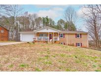 Charming brick home with a covered front porch, attached garage, and mature trees in a spacious yard at 1925 S Lafayette St, Shelby, NC 28152