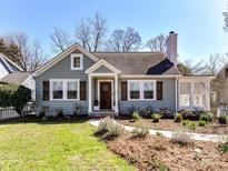 Charming home featuring a stone chimney, complemented by wood shutters and a well-manicured front yard at 2919 Park Rd, Charlotte, NC 28209