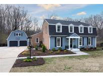 Charming two-story home with blue siding, black shutters, and a detached two-car garage at 4000 Bridgewood Ln, Charlotte, NC 28226