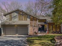 Two-story home featuring a two car garage, brick facade, dormer windows, a manicured lawn, and mature trees at 5213 Wood Lake Dr, Belmont, NC 28012