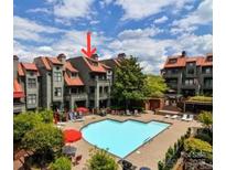 Exterior view of community pool and lounging area surrounded by gray townhomes with reddish-brown roofs at 9037 J M Keynes Dr, Charlotte, NC 28262