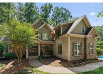 Charming exterior showcasing a stone and siding facade, complemented by a well-manicured lawn and mature trees at 109 Hawksnest Ln, Mooresville, NC 28117