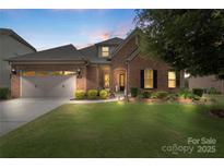 Charming brick home features a manicured lawn, attached garage, and inviting front entrance with manicured landscaping at 12726 Rusty Blackbird Way, Charlotte, NC 28278