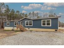 Inviting single-story home with blue siding, a wooden porch, and large windows at 2647 Dusty Trail Ln, Lancaster, SC 29720