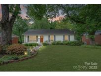 Charming single-story home featuring a well-manicured lawn, inviting walkway, and beautifully landscaped flowerbeds at 6126 Netherwood Dr, Charlotte, NC 28210