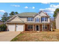 Charming two-story home with stone accents, a two-car garage, and a welcoming front porch under a blue sky at 631 Winding Branch Rd, Rock Hill, SC 29732