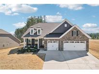 Beautiful two-story home with a brick facade, dormer windows, and a three-car garage at 1300 Dali Blvd, Mount Holly, NC 28120