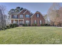 Charming two-story brick home featuring a well-manicured lawn, classic black shutters, and a welcoming front porch at 15100 Durmast Ct, Mint Hill, NC 28227