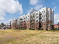 Apartment building featuring brick and metal facade with balconies, surrounded by a green lawn and blue sky at 2338 Yadkin Ave # 503, Charlotte, NC 28205