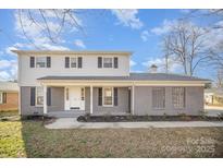 Charming two-story home with a welcoming front porch and manicured landscaping on a sunny day at 303 Bost St, Kannapolis, NC 28081