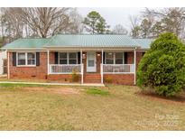 Charming red brick home with a green metal roof and a cozy front porch, complete with classic white railings at 4187 Bessie Hudson Rd, Lancaster, SC 29720