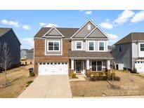 Charming two-story home with a brick and gray facade, attached garage and manicured lawn at 4233 Poplin Grove Dr, Indian Trail, NC 28079