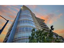 Modern high-rise building featuring expansive glass windows against a colorful sky at 505 E 6Th St # 804, Charlotte, NC 28202