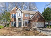 Charming two-story brick home with attached garage, arched entryway, and manicured front yard at 717 Meadow Lake Dr, Matthews, NC 28105