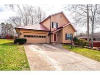 Charming tan home featuring a red metal roof, complemented by a spacious front yard and two-car garage at 1228 Hidden Creek Cir, Hickory, NC 28602