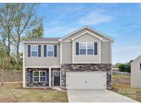 Charming two-story home featuring stone accents, gray siding, a two-car garage, and a well-maintained lawn at 124 Rustling Waters Dr, Mooresville, NC 28117