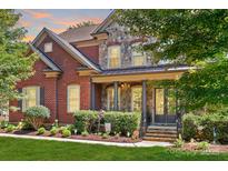 Charming stone and brick home with manicured lawn and mature trees, offering classic curb appeal at 13122 Long Common Pkwy, Huntersville, NC 28078
