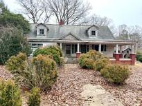Quaint home with dormers, covered porch, and mature landscaping, awaiting a creative renovation at 2412 Daves Dr, Shelby, NC 28152