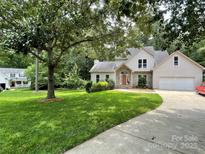 Charming home featuring a lush green lawn, mature trees, and an inviting driveway leading to the front entrance at 7306 Timbercreek Ct, Denver, NC 28037