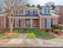 Charming red brick townhome featuring a cozy front porch with a bench swing at 9128 Kings Canyon Dr, Charlotte, NC 28210
