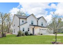 Beautiful new construction home boasts a three-car garage and a pristine lawn at 122 Round Rock Rd, Troutman, NC 28166