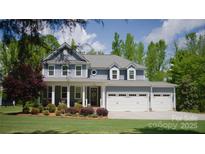 Charming two-story home featuring a manicured front lawn, attached three-car garage, and inviting front porch at 158 Country Lake Dr, Mooresville, NC 28115