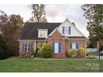 Charming brick home with blue shutters, dormer windows, a green door, and mature trees at 205 Kaitlyn Ln, Kings Mountain, NC 28086