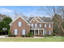 Imposing two-story brick home featuring symmetrical design, black shutters, mature landscaping and covered entryway at 518 Streamside Ln, Marvin, NC 28173