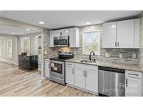 Updated kitchen features stainless appliances, granite counters, modern backsplash and wood look flooring at 98 Ring Sw Ave, Concord, NC 28025
