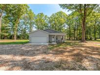 Charming single-story home with a welcoming front porch and a well-manicured lawn surrounded by mature trees at 1513 Fletcher Broome Rd, Monroe, NC 28112