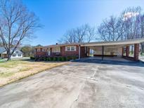 Charming brick ranch-style home featuring a carport and long driveway on a sunny day at 2310 Clay St, Kannapolis, NC 28083