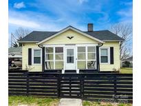 Charming yellow home featuring a cozy front porch and a stylish black fence at 101 Loya St, Mount Holly, NC 28120