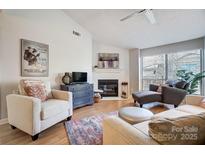 Inviting living room features a cozy fireplace, ample seating, and a large window with natural light at 1608 Sharon W Rd # 56, Charlotte, NC 28210