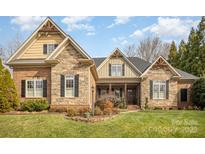 Charming brick and stone home featuring a manicured lawn and inviting front porch entrance at 2028 Fitzhugh Ln, Weddington, NC 28104