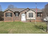 Charming brick home featuring stone accents, manicured lawn, and an American flag at 2339 Perry Rd, Denver, NC 28037