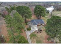 Expansive aerial view of a brick home nestled among mature trees, with a long drive and lake views at 805 Stack Rd, Monroe, NC 28112