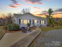 Charming single-story home featuring a walkway to the front door with blue outdoor seating at 4450 Flowes Store Rd, Concord, NC 28025