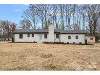 Charming, one-story home with a white brick exterior, black roof, and an inviting light blue front door at 6301 Vernedale Rd, Charlotte, NC 28212