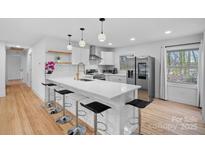 Modern white kitchen featuring an island with bar seating and stainless steel appliances at 6301 Vernedale Rd, Charlotte, NC 28212