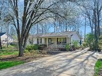 Charming single-story home with a covered front porch, a long driveway, and mature flowering trees in the front yard at 1906 Overhill Dr, Monroe, NC 28110