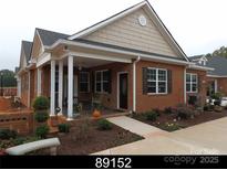 Charming brick home featuring a welcoming front porch, black shutters, and beautifully landscaped yard at 2227 Cashmere Ct, Denver, NC 28037