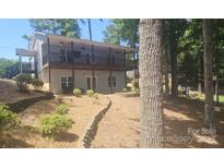 Two story home with a black porch, gray siding, and mature trees surrounding the property at 604 Fairway Shores Rd, Mount Gilead, NC 27306