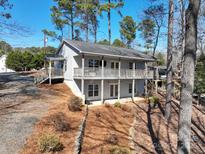 Charming two-story home features a spacious wraparound deck, inviting curb appeal, and serene wooded surroundings at 604 Fairway Shores Rd, Mount Gilead, NC 27306