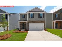 Charming two-story home with gray siding, stone accents, a two-car garage, and a well-manicured lawn at 107 Windstone Common Ln, Mooresville, NC 28117