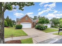 Charming brick home featuring an attached two-car garage, well-manicured lawn, and lush landscaping at 14309 Stonewater Ct, Fort Mill, SC 29707