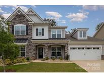 Charming two-story home with a stone facade, covered porch, manicured lawn, and two car garage at 17015 River Race Dr, Huntersville, NC 28078