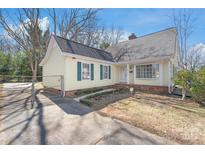 Charming yellow house with green shutters, fenced driveway, and a well-maintained front lawn at 6626 Somersworth Dr, Charlotte, NC 28215