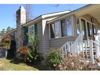 Charming home features a stone chimney, complemented by well-maintained landscaping and classic green shutters at 752 Pinehaven Dr # 105, New London, NC 28127