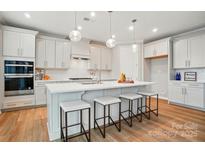 Bright kitchen features a large island with seating, stainless steel appliances, and modern light fixtures at 9930 Cask Way, Huntersville, NC 28078